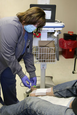 A wound care nurse places a monitor on a patient for a PAD screen.