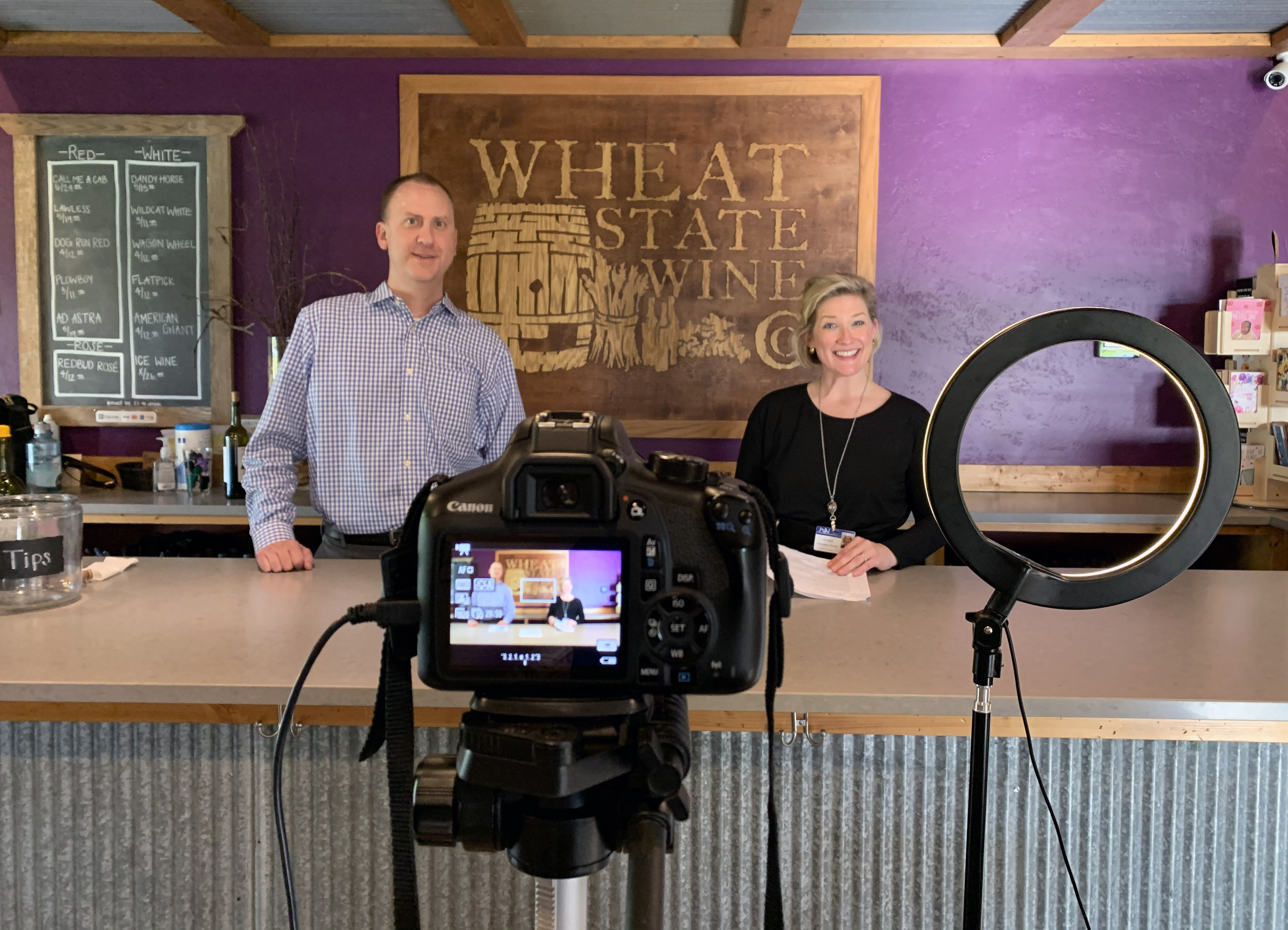 Behind the counter at Wheat State Wine Co., Union State Bank Winfield Market President Cory Helmer and William Newton Healthcare Foundation Director Annika Morris pre-record elements of the upcoming virtual gala benefiting William Newton Hospital.