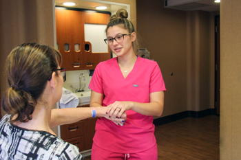 Nurse assistant Ashton Richardson places an American flag wristband on a veteran at William Newton Hospital.