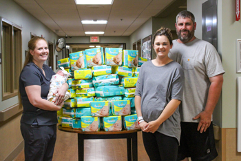 Tarena Sisk, CNM, APRN, left, embraces the 1000th baby she delivered at the William Newton Hospital Family Birthing Center, while parents Stephanie and Brad Moberly happily receive 1000 diapers.