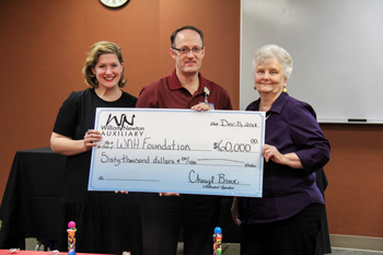 Auxiliary President Georgia Larson, right, presents a check for $60,000 to William Newton Hospital Chief Executive Officer Ben Quinton, center, and William Newton Healthcare Foundation Director Annika Morris, left, at the organization’s annual holiday party.