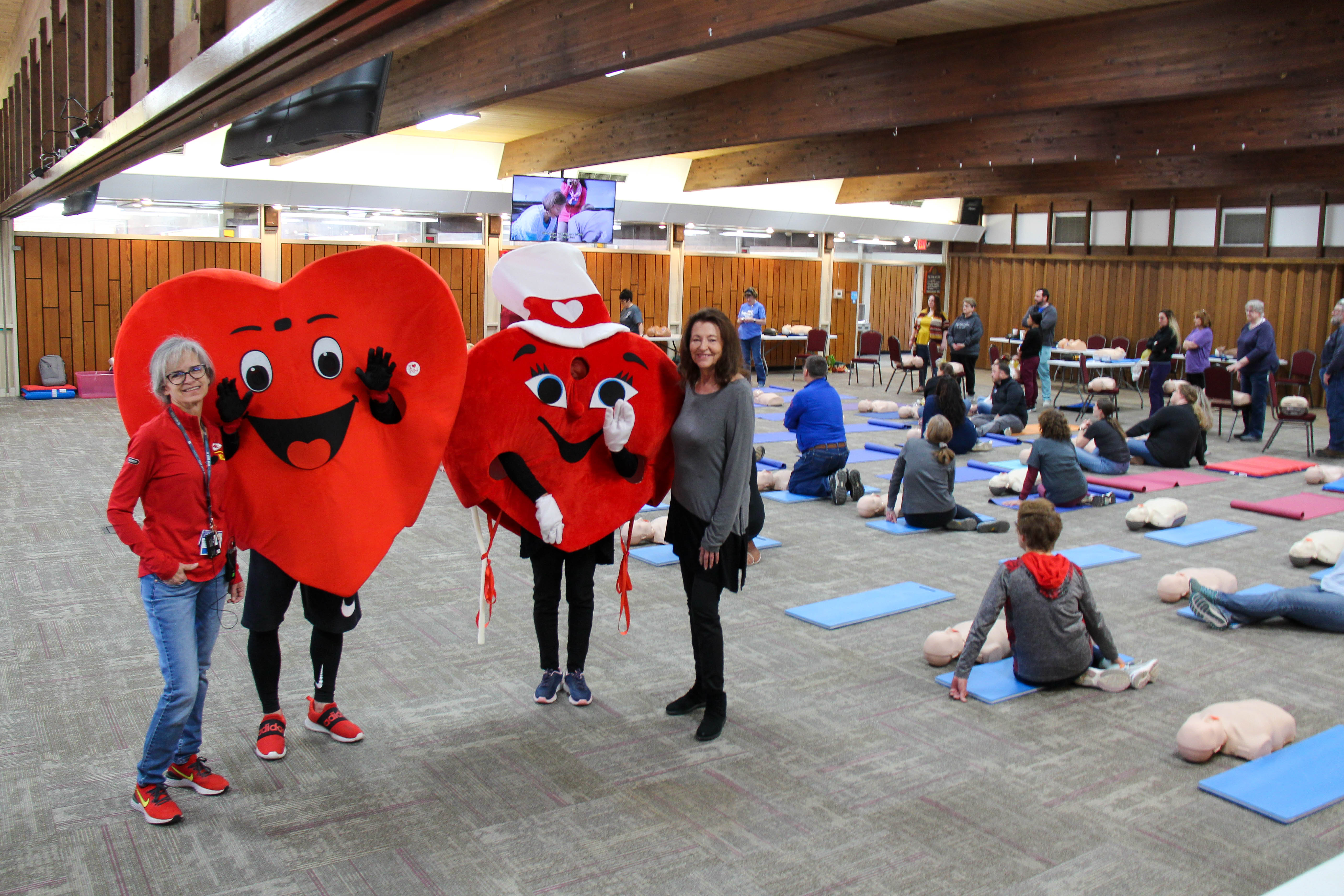Standing with the two Beats Go On mascots Willy & Mary Beat, co-chairs Mel Burnett (left) and Paula Radcliff (right) proudly host participants in the community-wide CPR training at Baden Square.